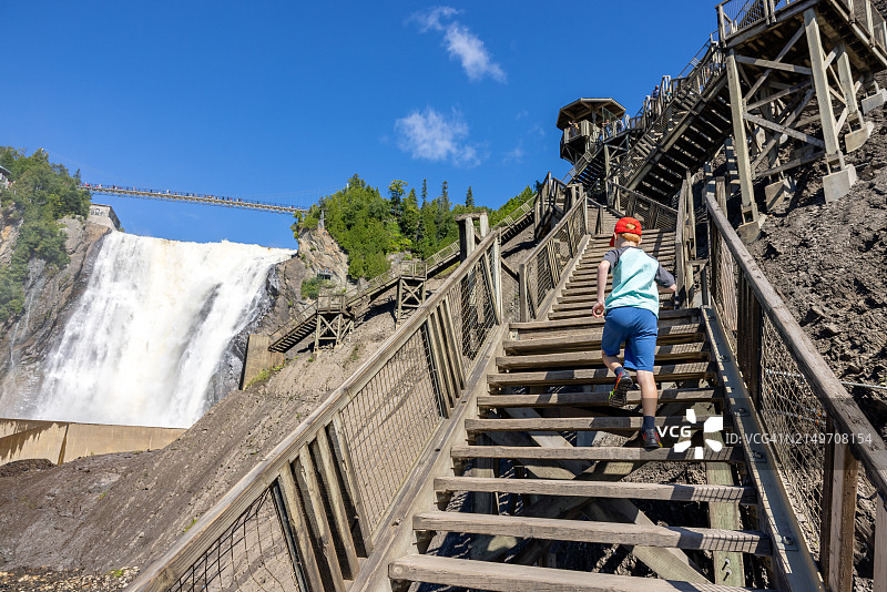 夏季在加拿大魁北克市蒙莫朗西瀑布爬楼梯的男孩图片素材