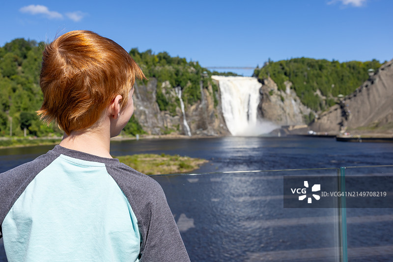 在加拿大魁北克市，夏季观看蒙莫朗西瀑布的男孩图片素材