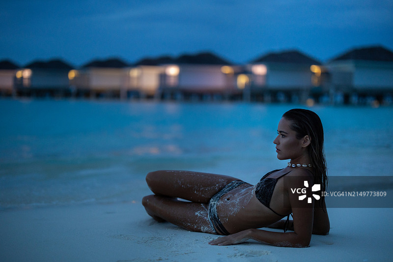 年轻漂亮的女人在傍晚的海滩上放松身心。图片素材