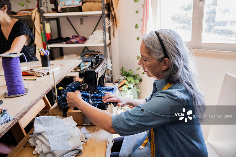 老年妇女在工作室缝纫衣服图片素材