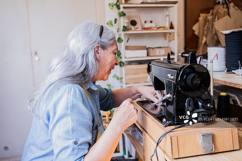 老年妇女在工作室缝纫衣服图片素材
