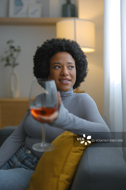 在家放松，喝着一杯粉红葡萄酒，微笑的爆炸头女人图片素材