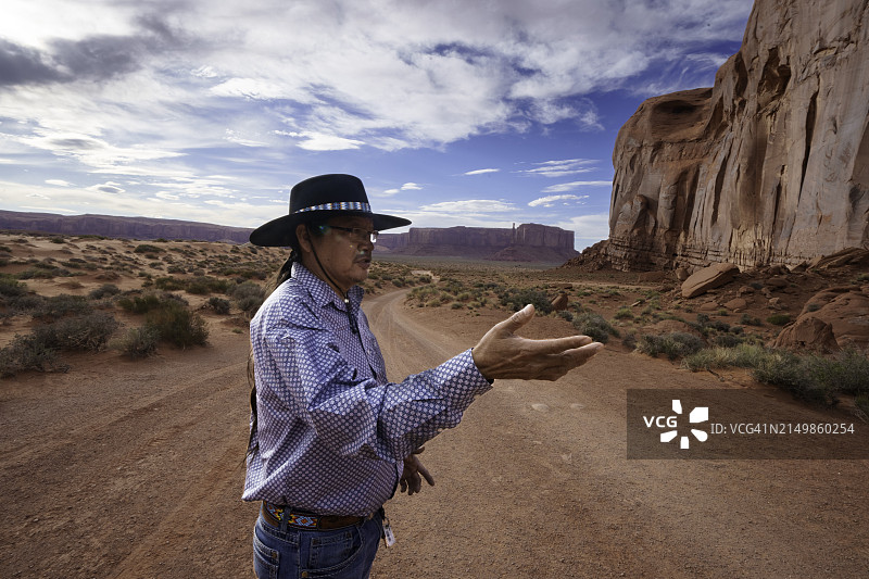 纳瓦霍族导游在亚利桑那州北部纪念碑谷部落公园的黄昏时分讲解孤山和风景，并协助摄影图片素材