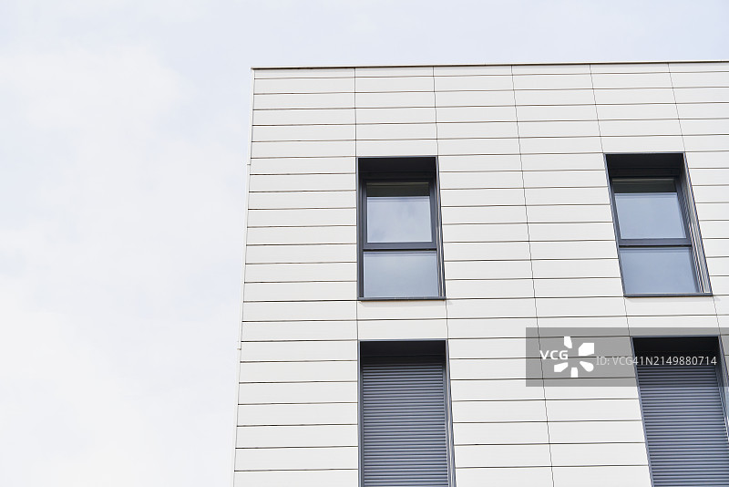 建筑物中带窗公寓的外部低角度视图，天空为背景图片素材