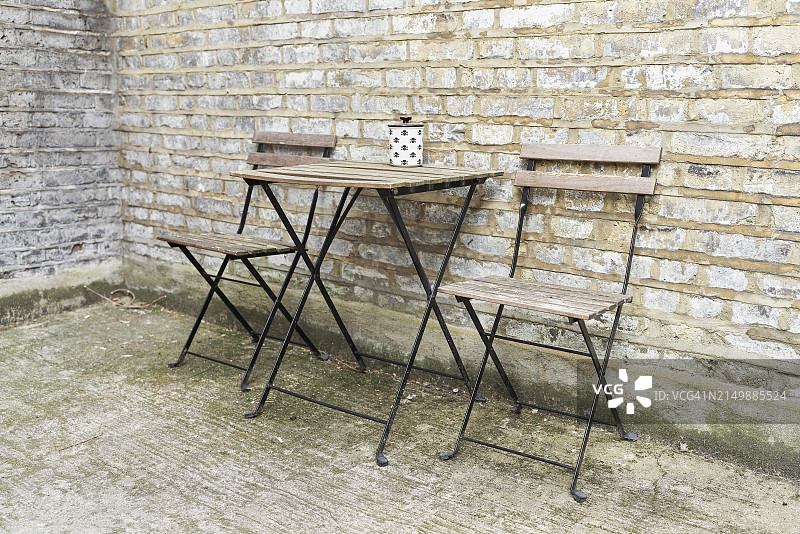 桌子的侧面视角，室外砖墙房屋，空椅子，无人图片素材