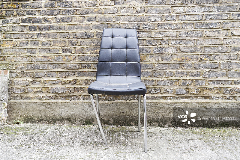 砖墙外的折叠金属腿空椅子正面图图片素材