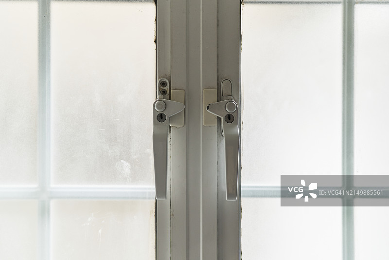 阳光照射房间玻璃窗上的金属格栅特写图片素材