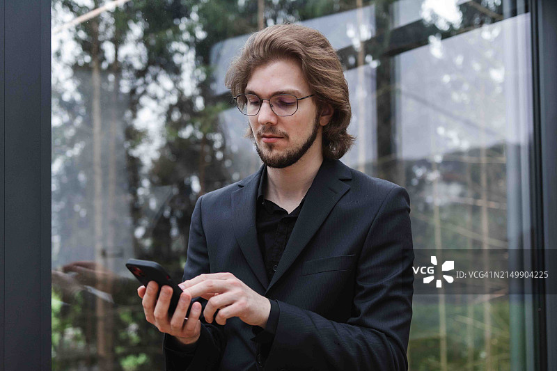 在办公室发短信的年轻男商人图片素材