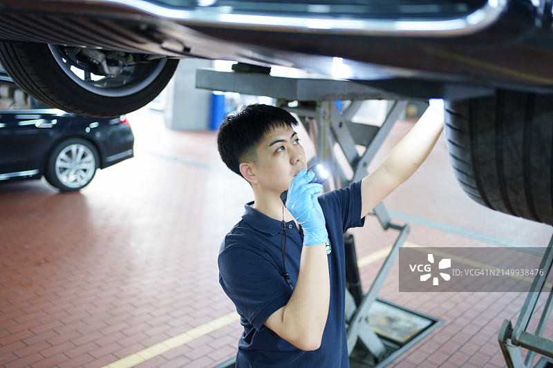 检查汽车底盘的亚洲工人图片素材