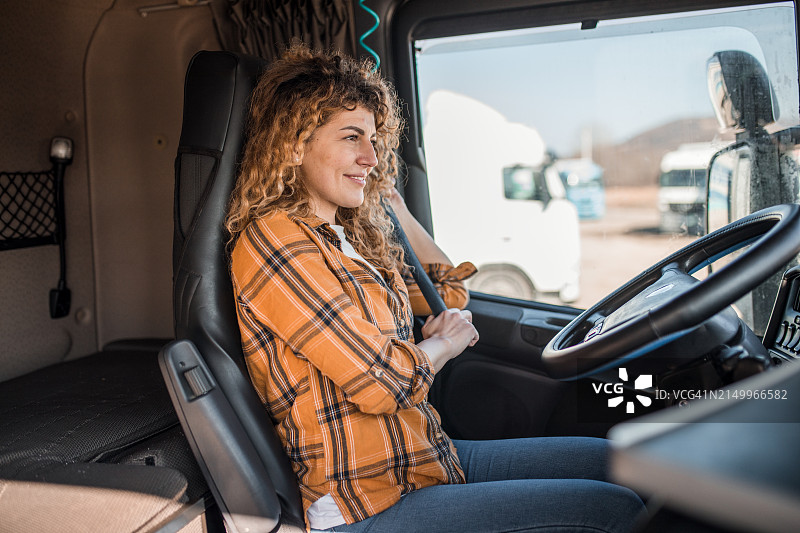 微笑的女卡车司机在开车前系好安全带图片素材
