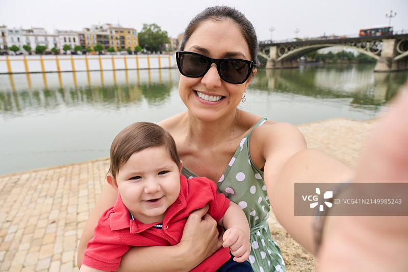 母亲和儿子在瓜达尔基维尔河畔的自拍，特里亚纳桥，塞维利亚，西班牙图片素材