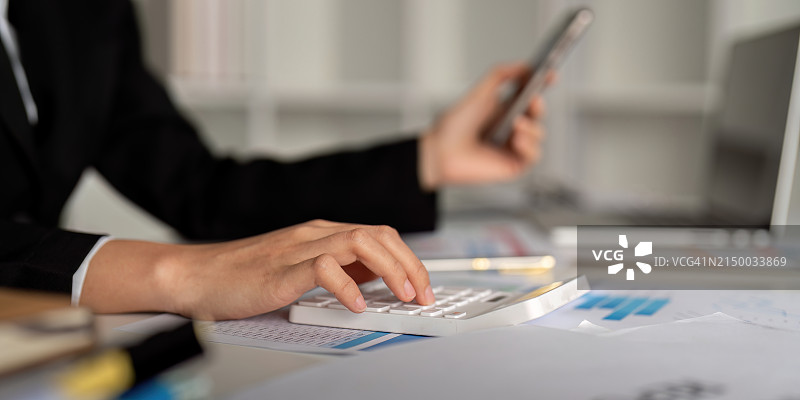 商务女士在办公室的办公桌上使用计算器图片素材