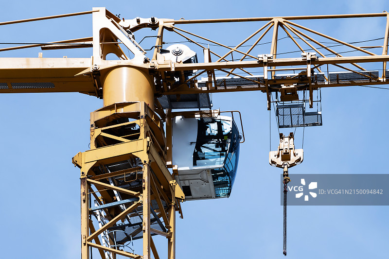蓝色天空下的黄色高大起重机的吊钩和小屋图片素材