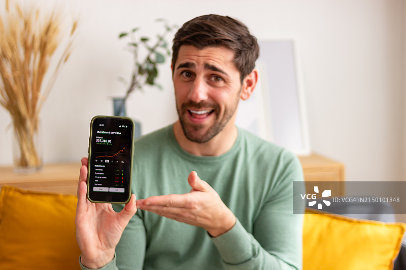 兴奋的男人在智能手机屏幕上展示投资增长图片素材