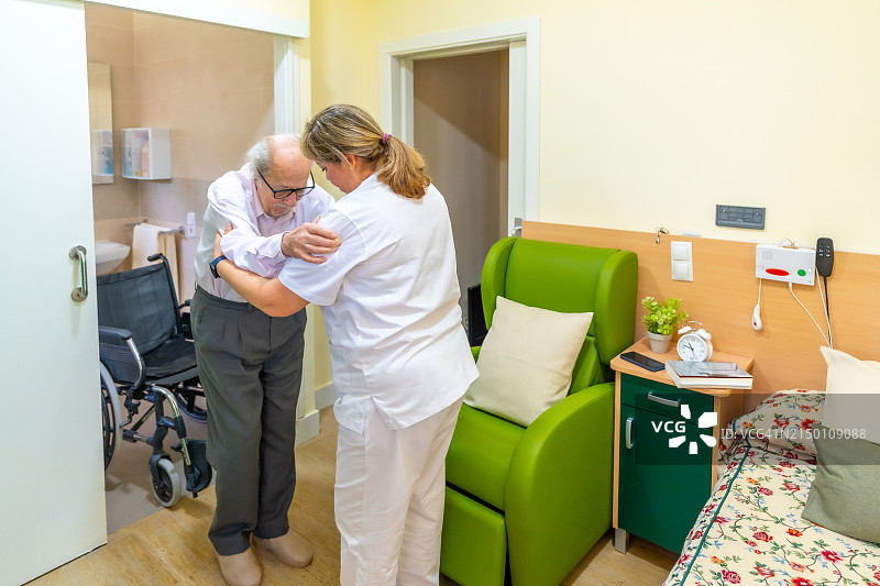 护理人员搀扶老年男子站立图片素材