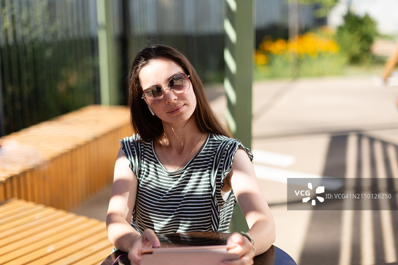 年轻女人在阳光明媚的日子里在户外使用平板电脑工作图片素材