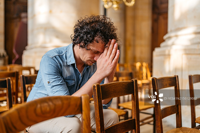 在巴黎教堂祈祷的年轻男人图片素材