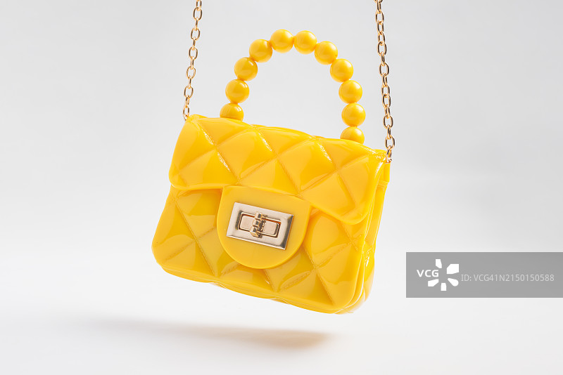 影棚拍摄的金色链条悬挂设计师手提包图片素材