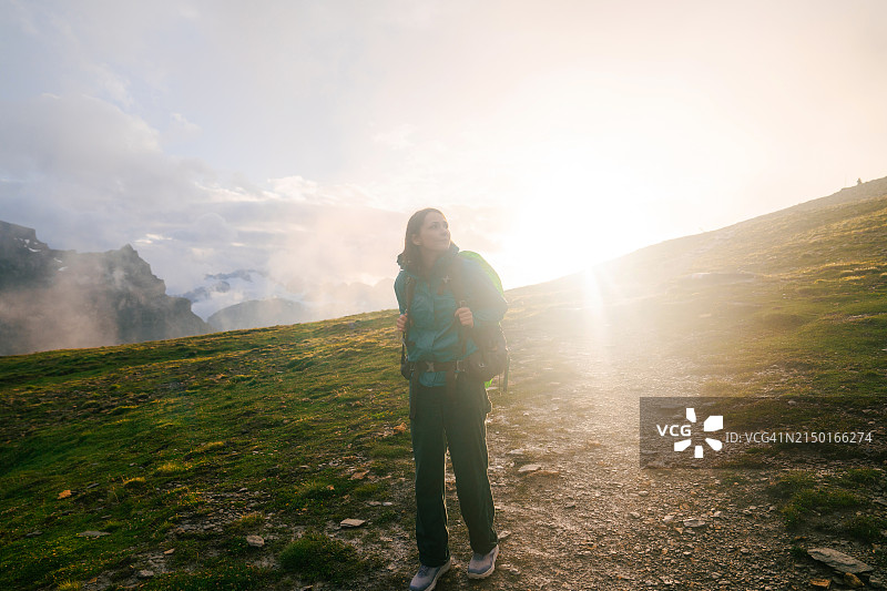 女人在瑞士阿尔卑斯山高地日落时徒步旅行图片素材