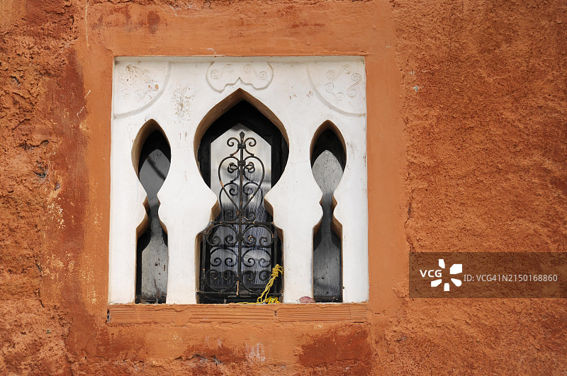 Chefchaouen，橙红色墙壁上的拱形窗户和锻铁格栅图片素材