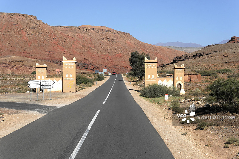 阿伊特·本·哈杜，通往沙漠的空旷公路，两侧是拱门和路标，非洲摩洛哥南部阿特拉斯山脉图片素材