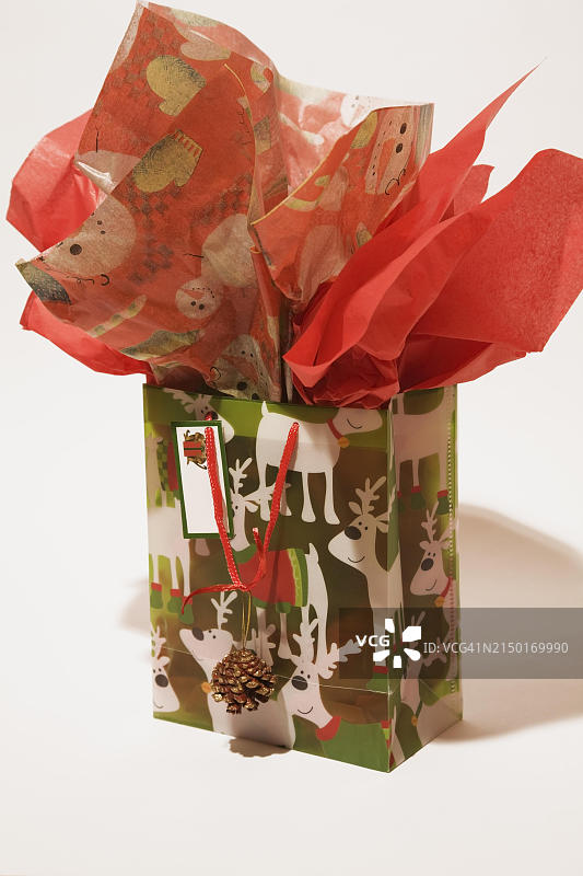 白色背景上带有驯鹿图案和红色丝绸纸装饰的圣诞礼品袋特写，魁北克，加拿大，北美图片素材