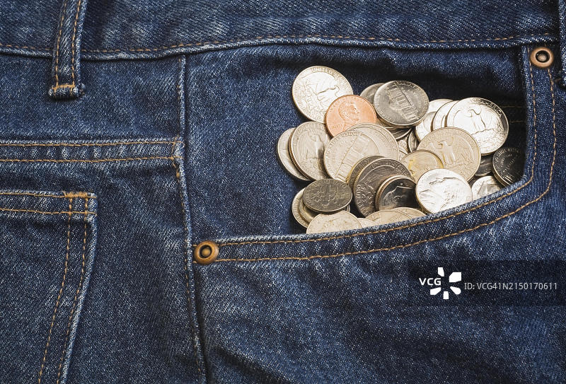 蓝色牛仔裤前袋中鼓出的美元硬币特写图片素材