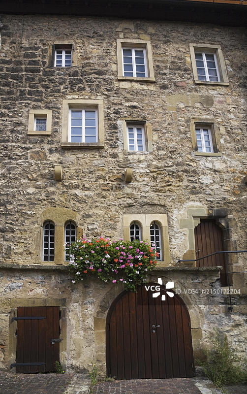 德国巴德温普芬，装饰着彩色天竺葵的老石头建筑外墙图片素材