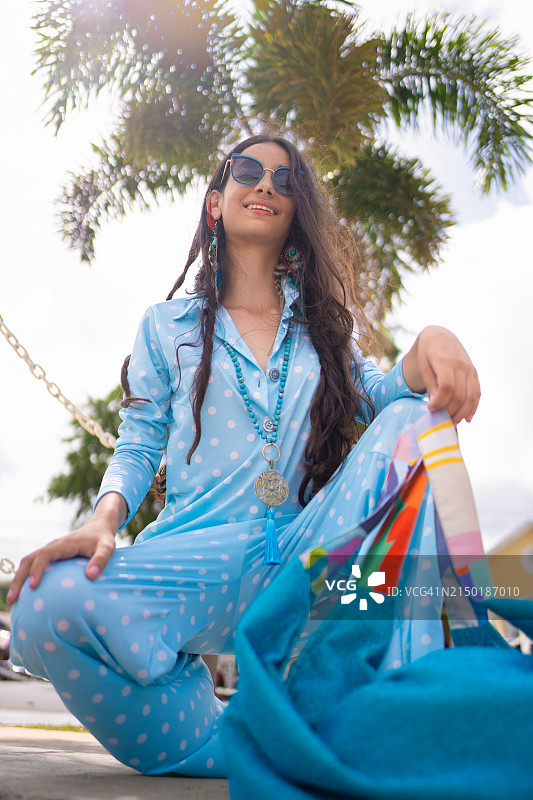 年轻女子戴着波西米亚风太阳镜，时髦地微笑图片素材