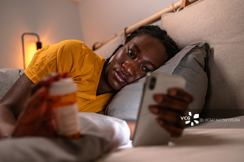 夜晚，年轻女人在线阅读药品信息图片素材