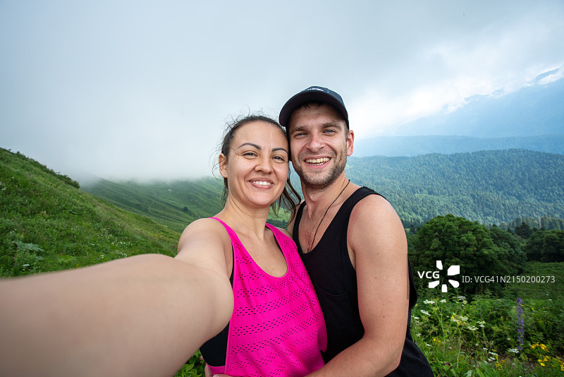 快乐的夫妇在山上拥抱并自拍图片素材