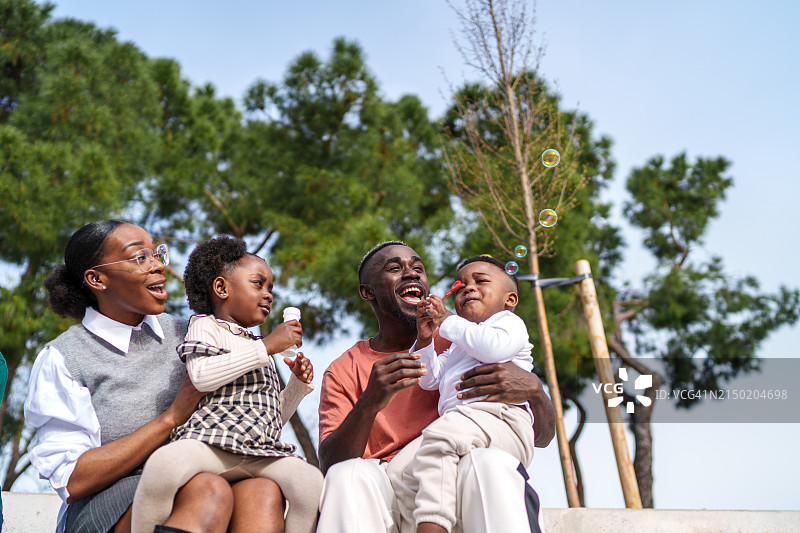 捕捉快乐：非洲家庭在阳光明媚的日子里玩泡泡图片素材
