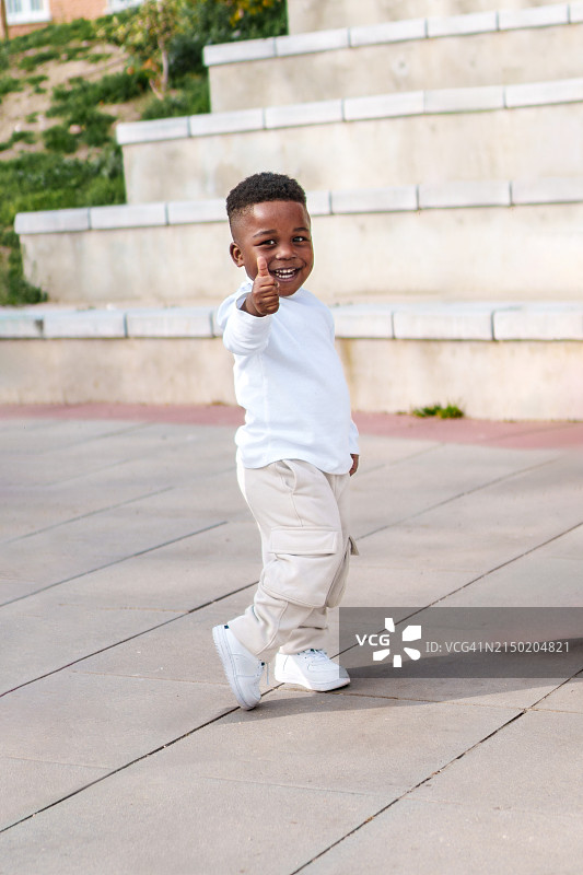 在公园里竖起大拇指的可爱的非洲男孩图片素材