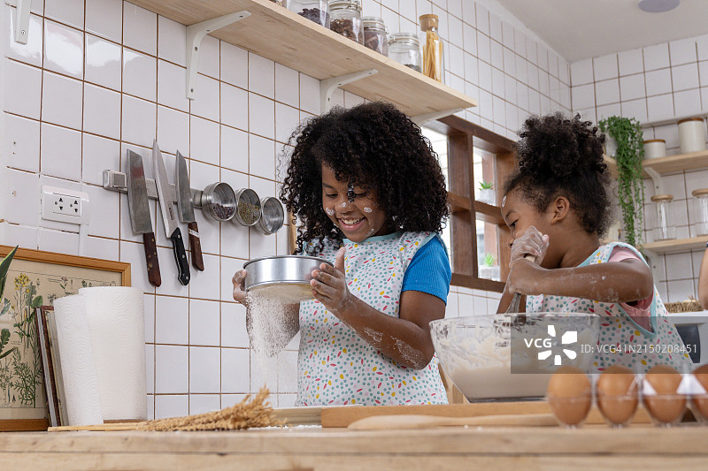 两个孩子在厨房里快乐地练习烹饪图片素材