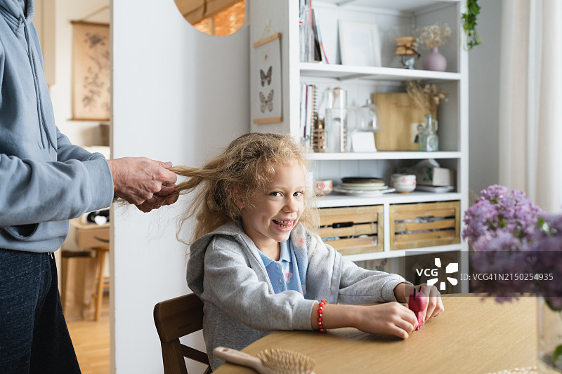 父亲帮女儿整理上学准备并梳头发图片素材