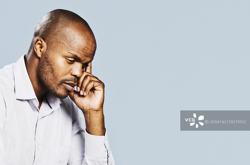 在浅蓝色背景上看起来担心、悲伤或沮丧的英俊男人图片素材