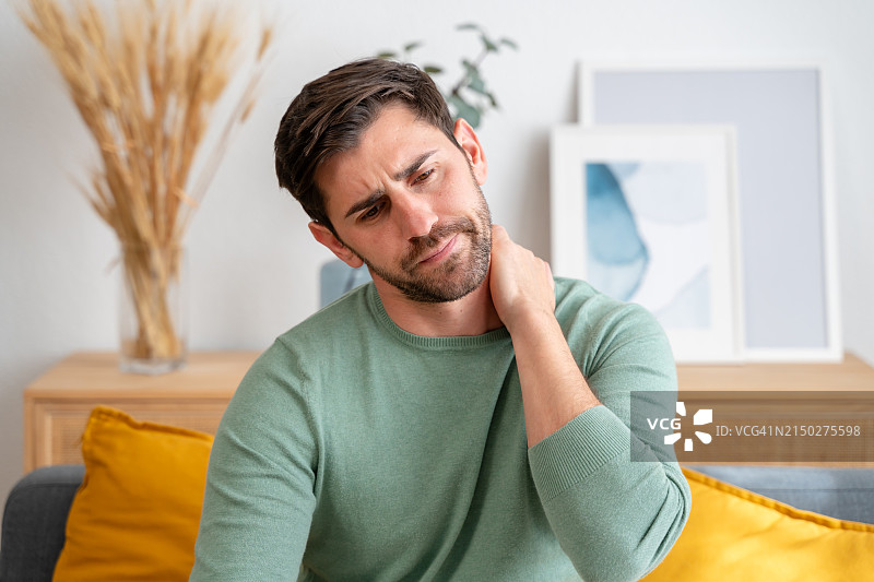 年轻男子在家感到颈部疼痛图片素材