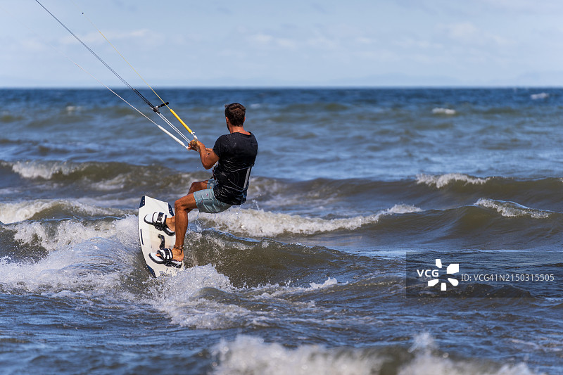 男子紧抓风筝，在风筝板上乘风破浪图片素材