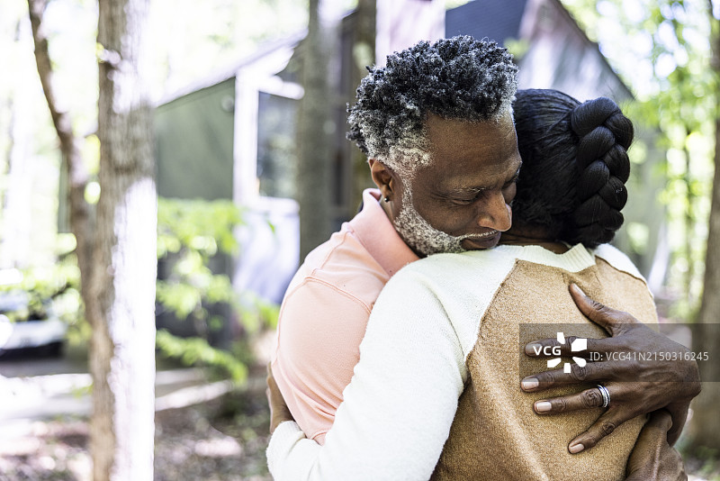 在郊区住宅前拥抱的老年夫妇图片素材