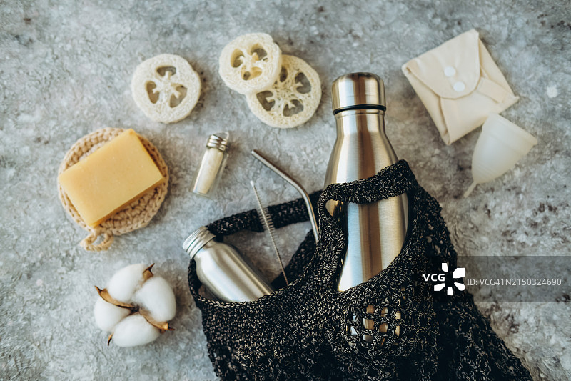 金属水壶、卫生配件、饮用吸管和深色网袋中的钢制清洁刷图片素材