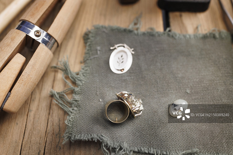 珠宝工匠在乡村木桌上手工制作戒指和工具图片素材