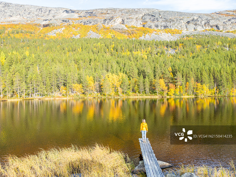 站在湖边码头上的孤独女子远景图片素材