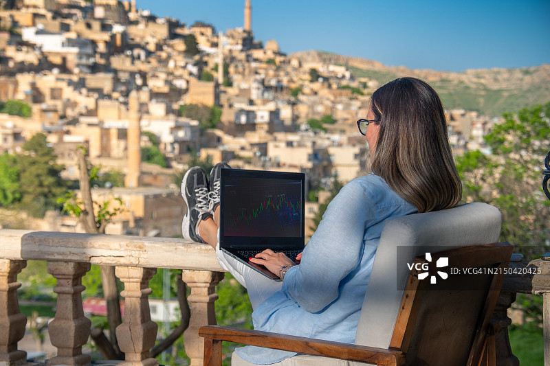 女商人使用笔记本电脑，城市景观为背景图片素材