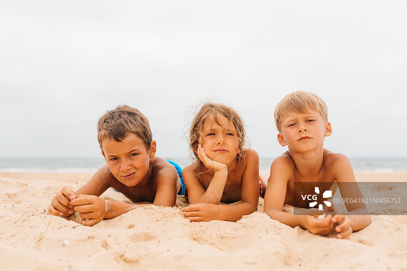 孩子们躺在沙滩上，暑假感到无聊图片素材