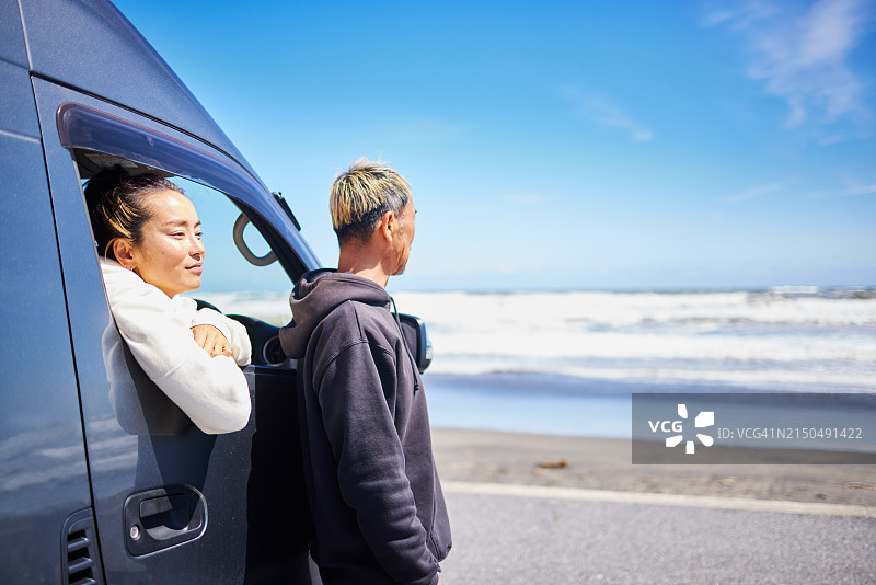 一对情侣在露营车里眺望大海的侧面照图片素材
