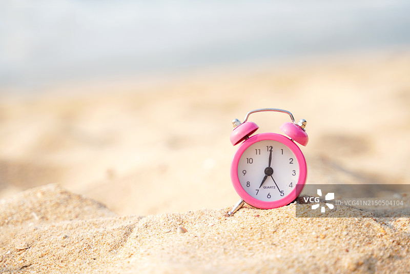 沙滩背景上的粉色复古时钟，有海星和渔船，留白区域。夏季概念图片素材
