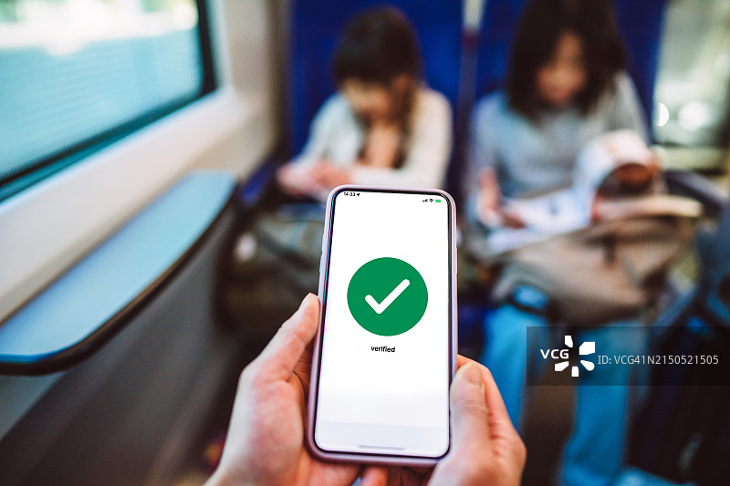 使用数码设备进行旅行计划：旅客在火车上用智能手机预订车票图片素材