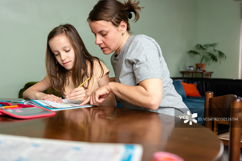 女人坐在餐厅的桌旁和女儿一起做作业图片素材