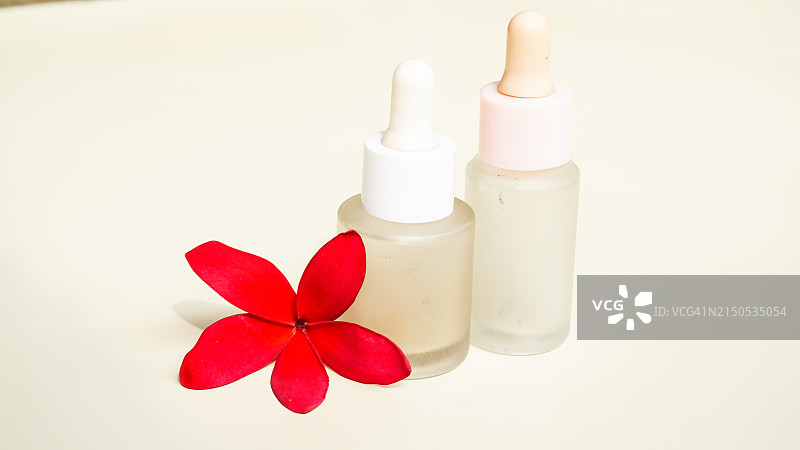白色背景上的安瓿滴管精华液罐和红色花朵特写图片素材