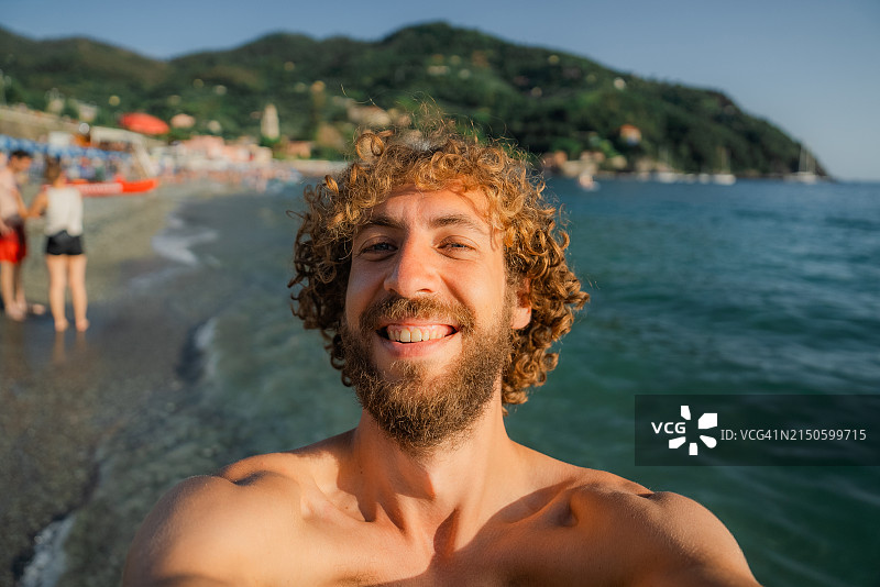 在地中海沿岸度假的卷发男子自拍图片素材